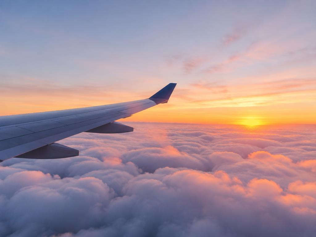 Representative photograph of an aircraft wing above clouds at sunrise